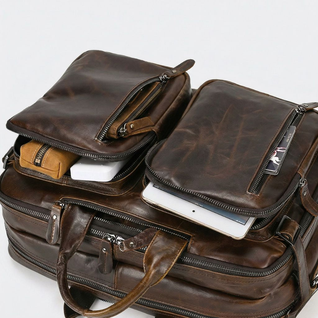 Poches avant ouvertes révélant une tablette blanche, un chargeur portable et une trousse cognac patiné
