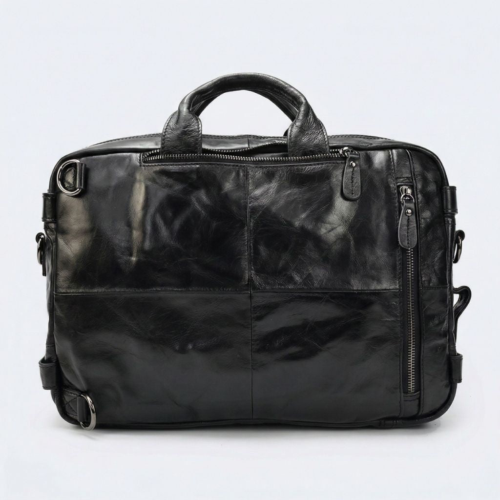 Verso du sac en cuir noir patiné, quatre panneaux cousus, attaches bretelles et fermeture latérale verticale