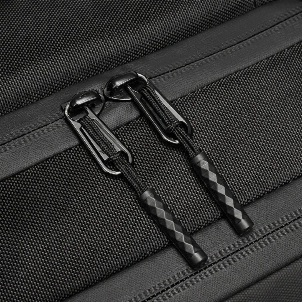 Detail des tirettes de fermeture eclair noires texturees sur sac a dos business en toile Oxford resistante