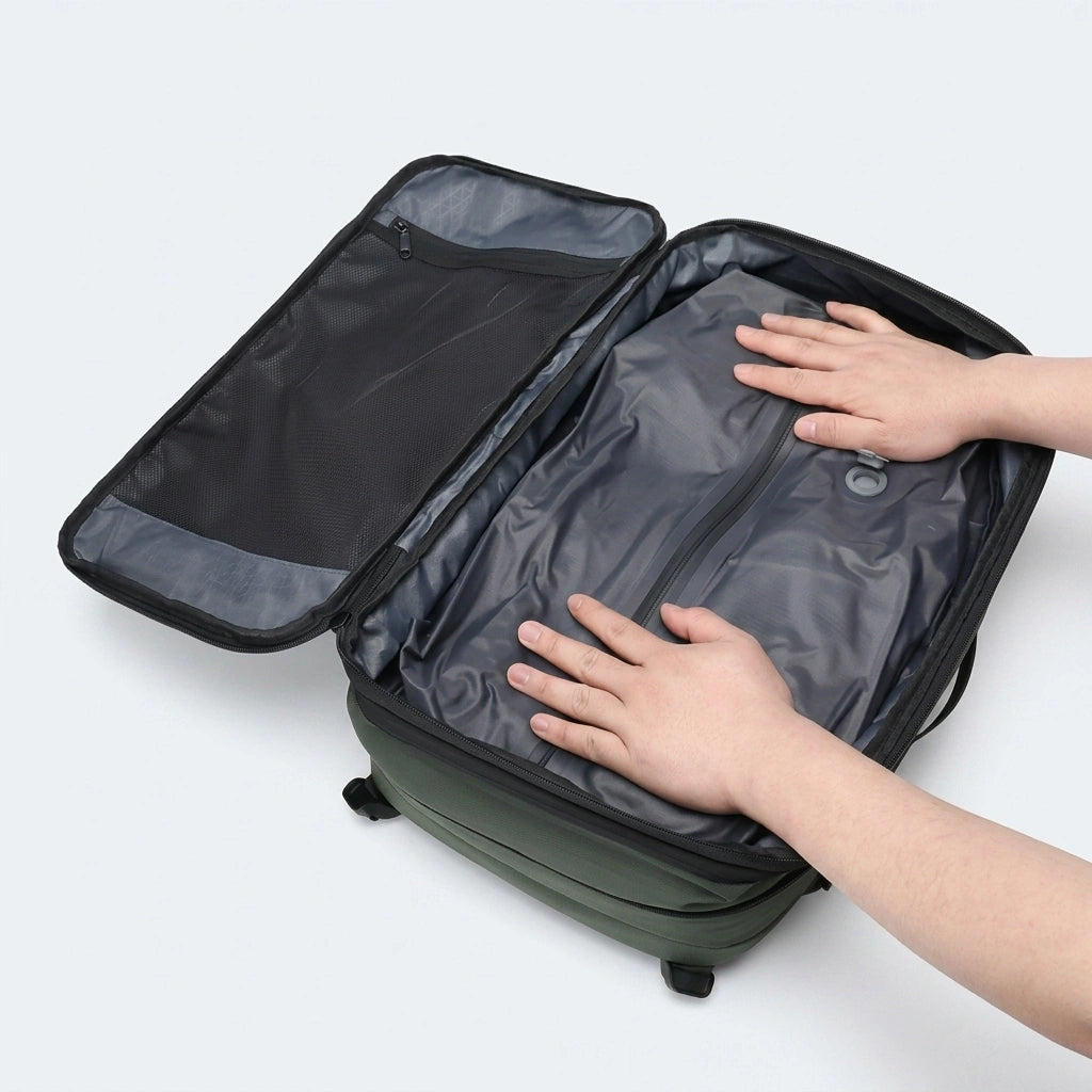 Mains appuyant sur le sac de compression pour évacuer l'air dans le sac à dos voyage vert ouvert
