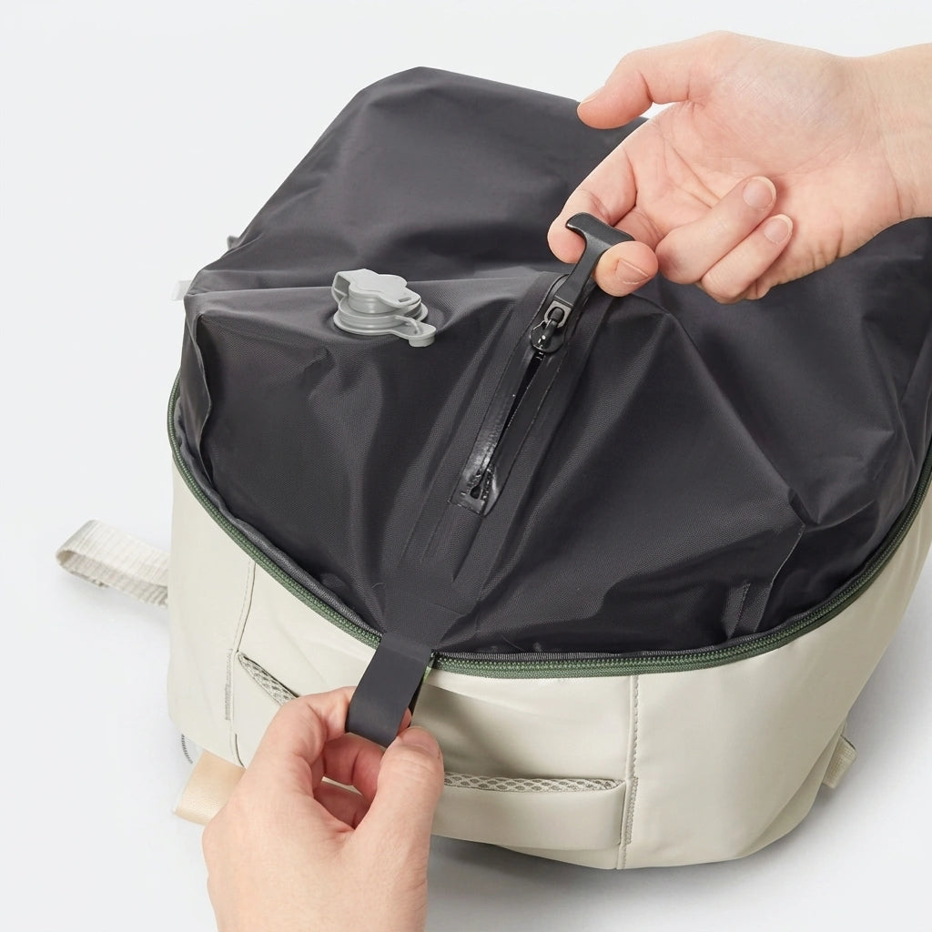 Gros plan sur le sac de compression sous vide noir intégré au sac à dos beige avec valve et fermeture éclair