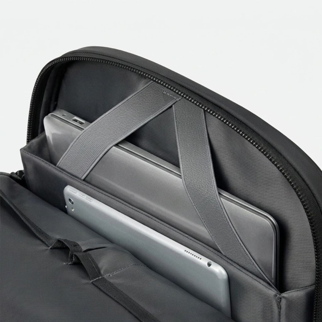 Compartiment laptop ouvert du sac à dos de voyage noir avec ordinateur et tablette maintenus par sangles
