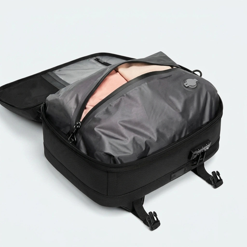 Sac à dos de voyage noir ouvert montrant la housse de compression sous vide grise contenant des vêtements