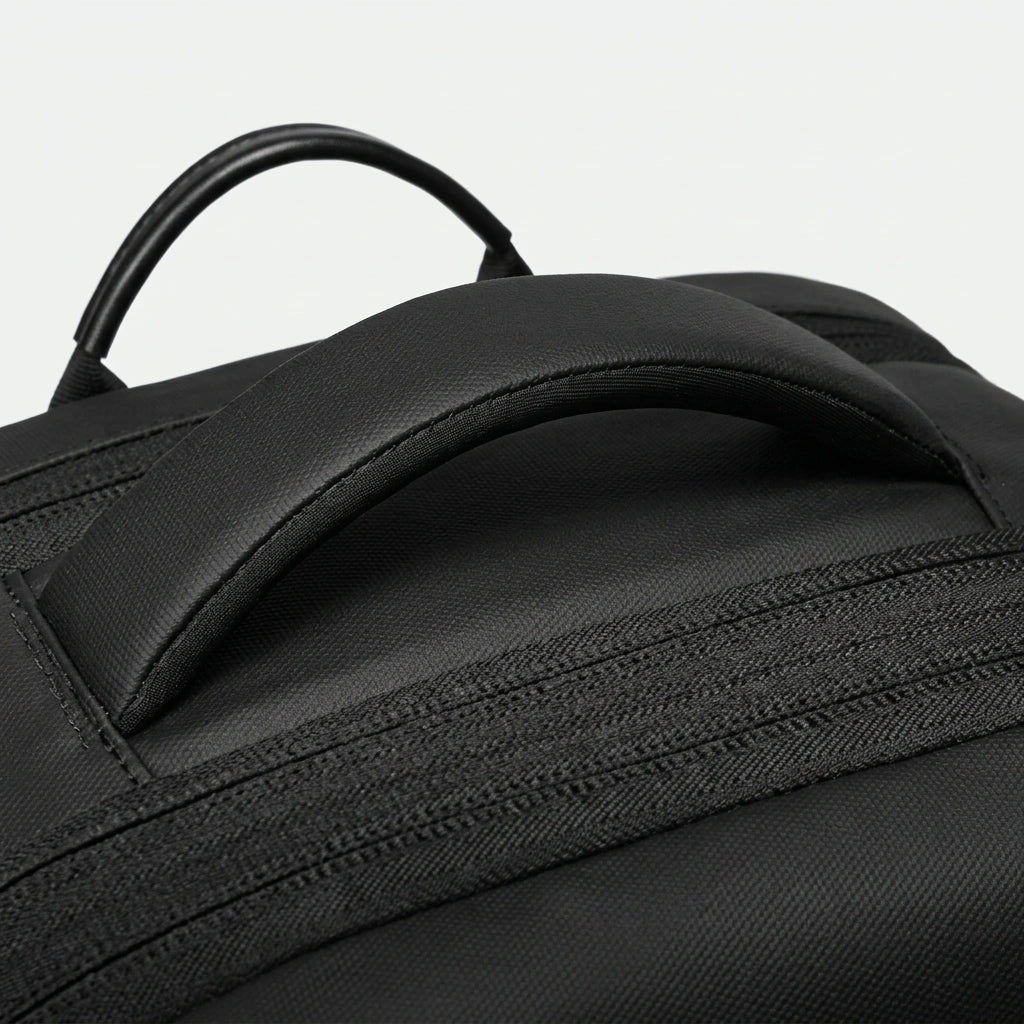Gros plan de la poignée supérieure rembourrée du sac à dos de voyage noir en toile Oxford texturée noire