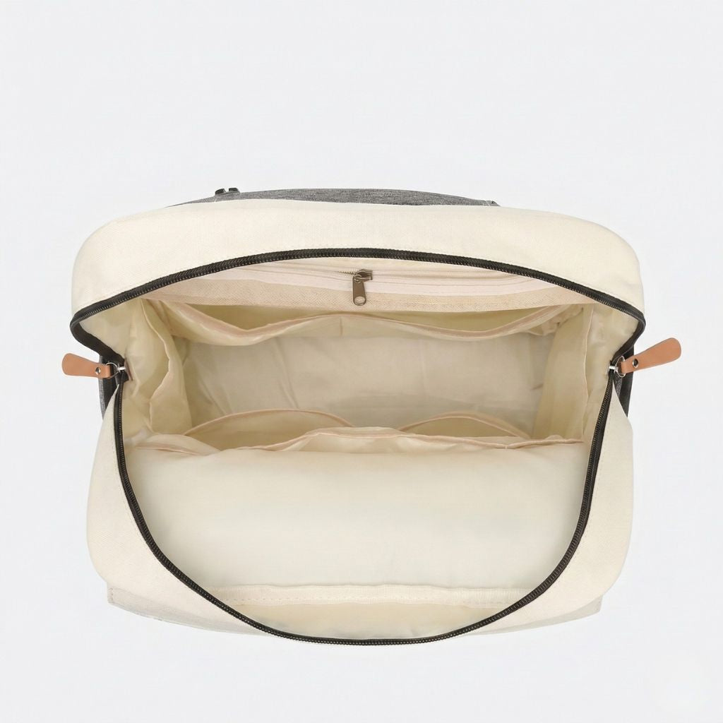 Intérieur spacieux du sac à langer ouvert, doublure beige crème avec multiples compartiments et poche zippée