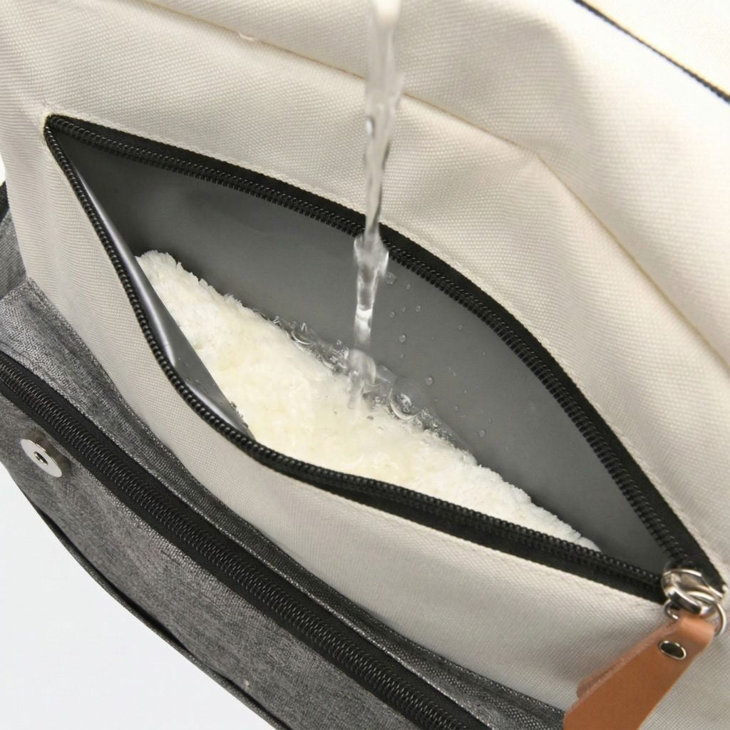 Gros plan d'une poche imperméable du sac à langer avec de l'eau versée dessus, démontrant sa résistance à l'eau