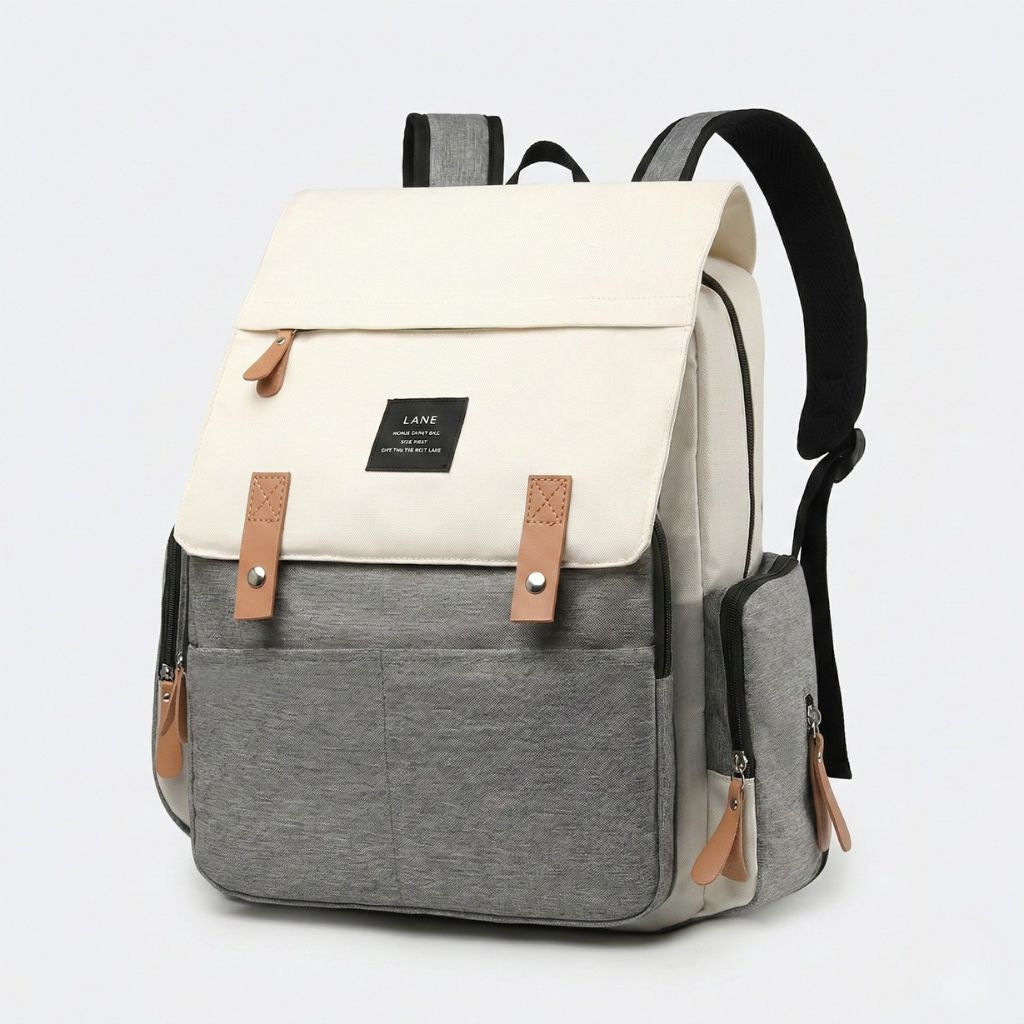Sac à dos à langer bicolore beige crème et gris, vue 3/4 avant, multiples poches et finitions cuir camel