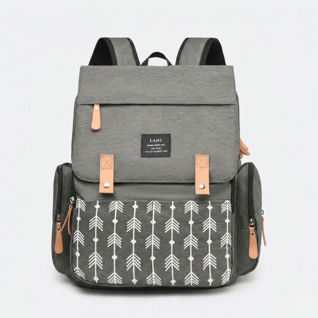 Sac à dos à langer gris chiné motif flèches, vue frontale, rabat supérieur avec passants cuir et fermeture pression