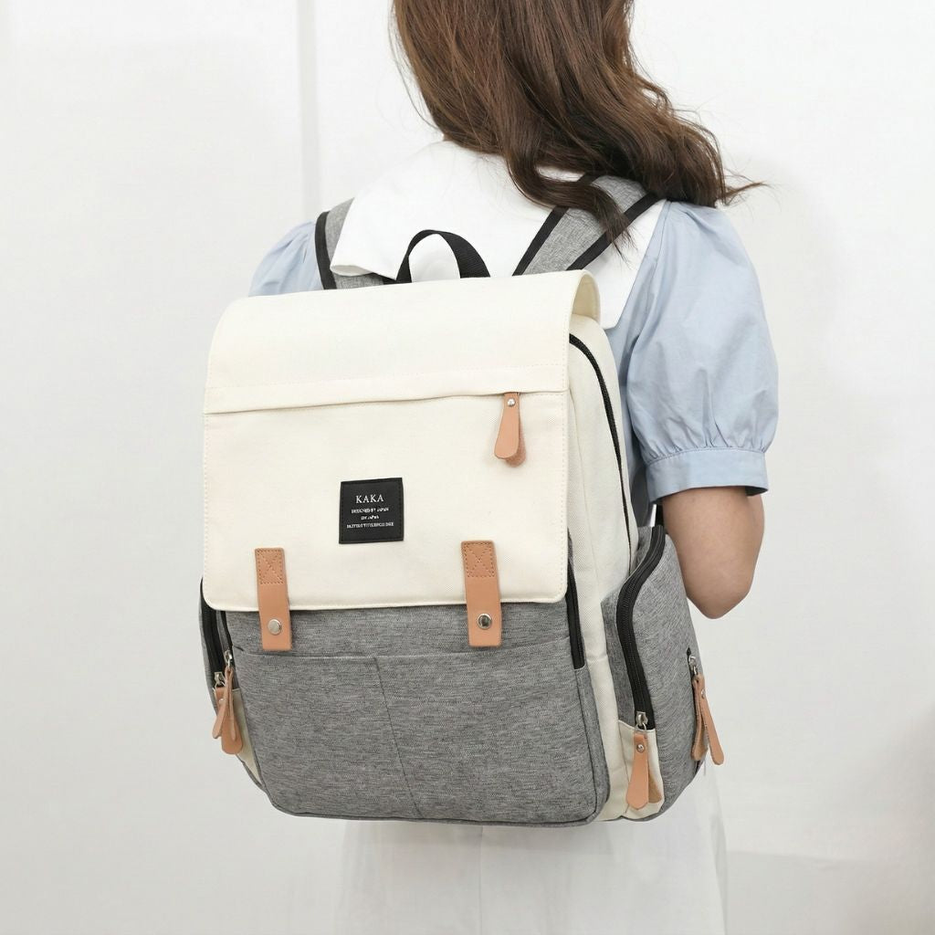 Femme portant le sac à langer bicolore beige et gris de 3/4 dos, style élégant pour mamans au quotidien