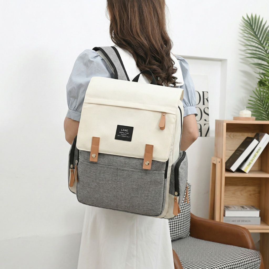 Sac à langer beige crème et gris accroché au guidon d'une poussette, idéal pour les sorties en famille