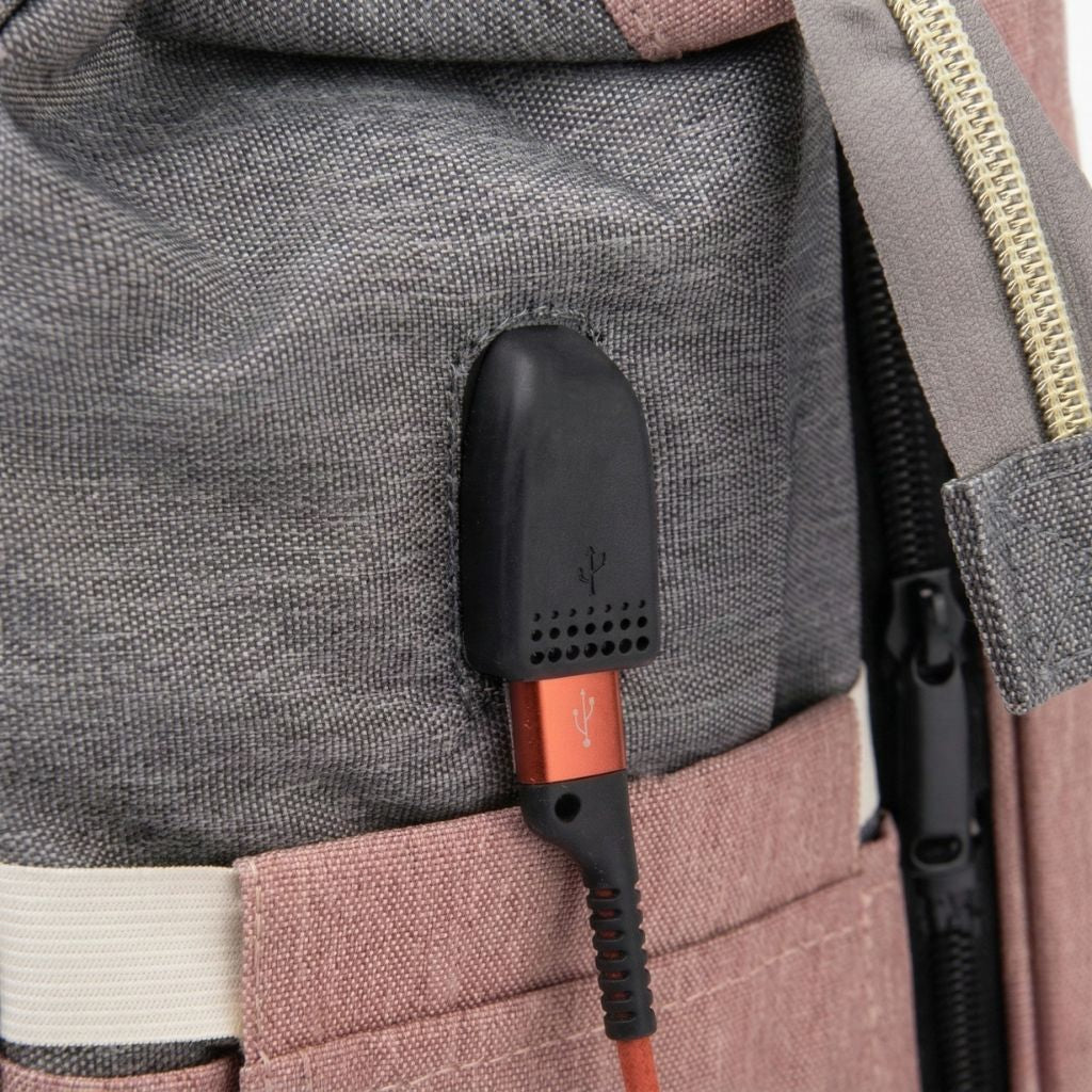Gros plan du port USB externe du sac à langer rose poudré et gris avec câble de recharge orange branché
