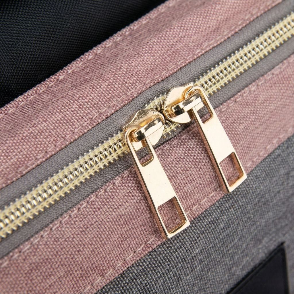 Gros plan des doubles tirettes métalliques dorées de la fermeture éclair principale du sac à langer rose