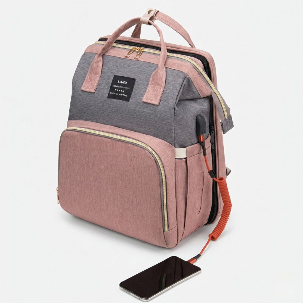 Sac à langer rose poudré et gris vu de 3/4 avec port USB externe et câble de recharge orange visible