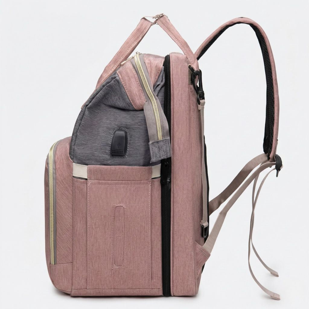 Vue de côté du sac à langer rose poudré avec berceau déployable intégré en structure grise visible