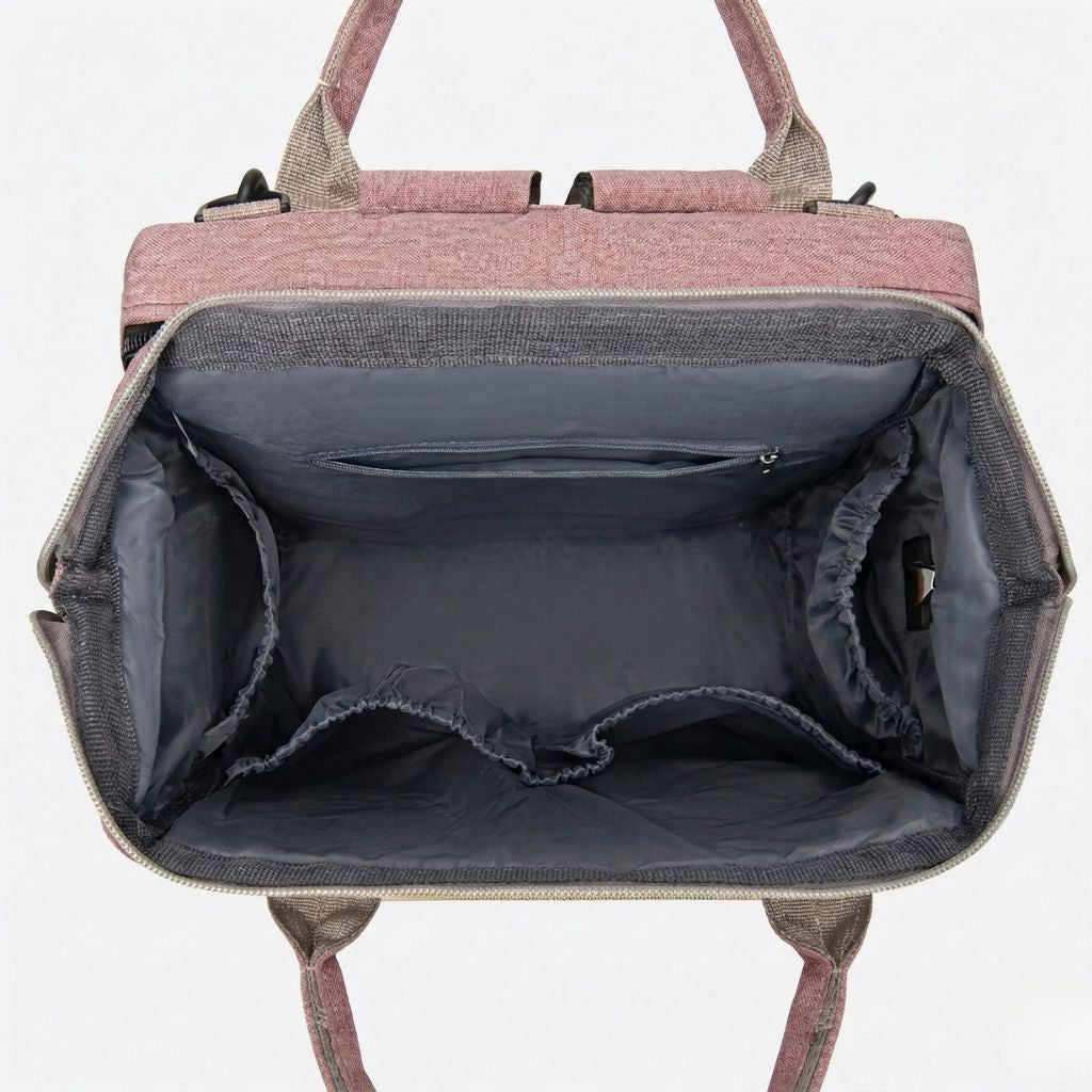 Intérieur du sac à langer rose poudré ouvert : porte-biberons élastiques et vaste compartiment principal