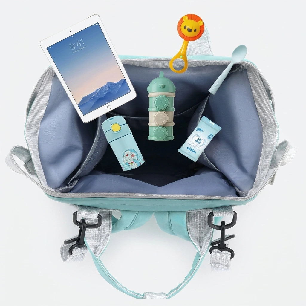 Intérieur du sac à dos à langer ouvert avec tablette, accessoires bébé et tétine, coloris vert menthe