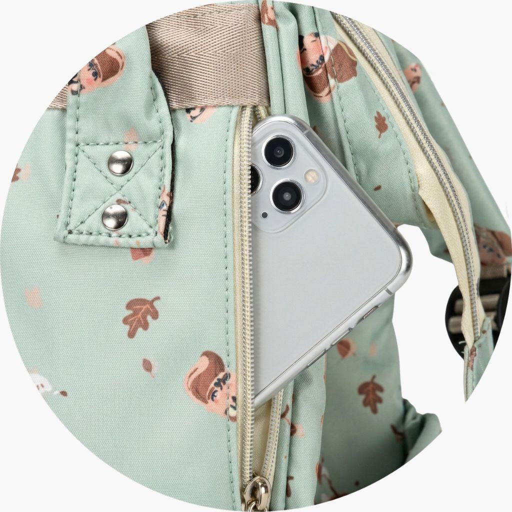 Gros plan circulaire de la poche frontale zippée du sac à langer avec un smartphone rangé à l'intérieur