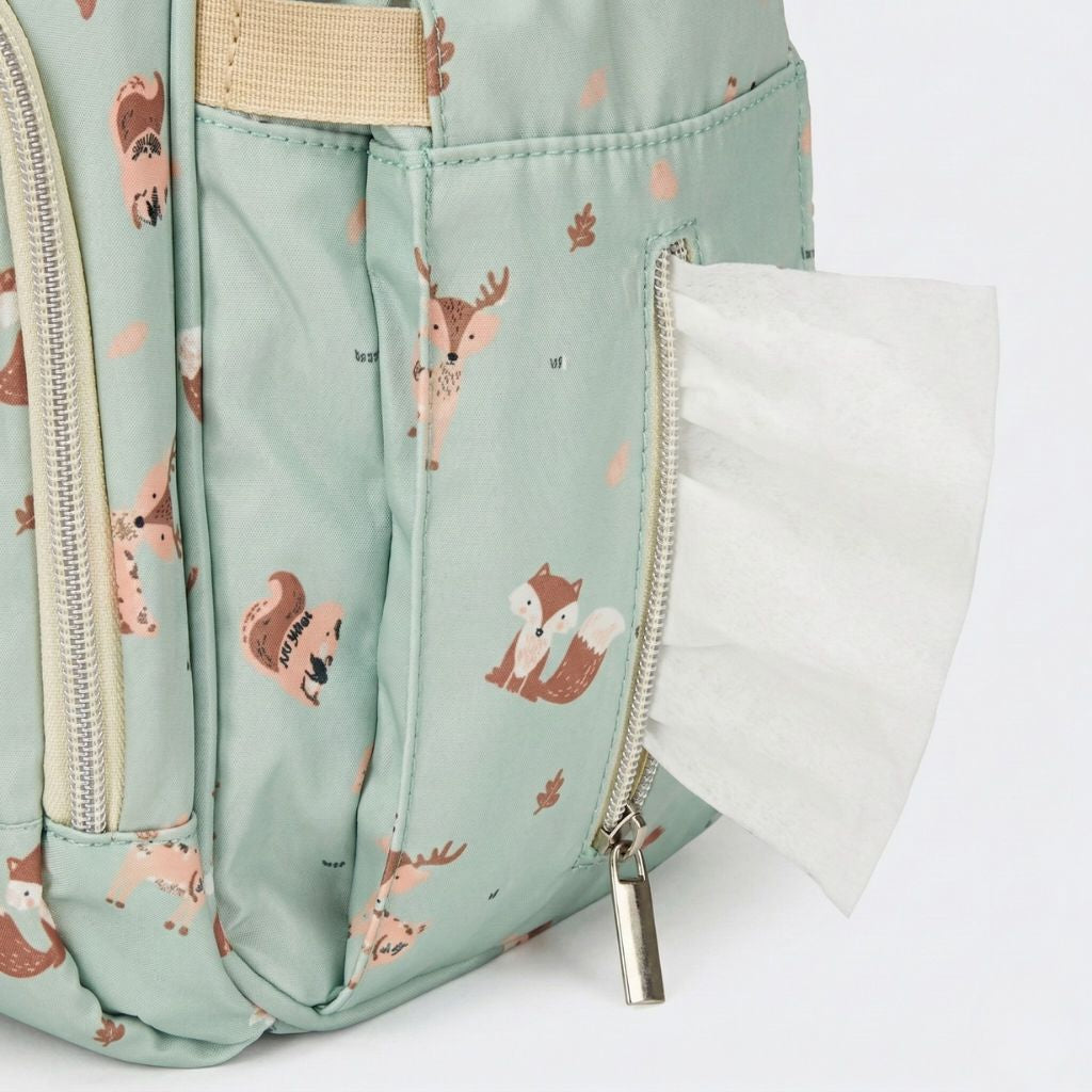 Poche latérale zippée du sac à langer vert sauge avec motif forêt, révélant des lingettes bébé