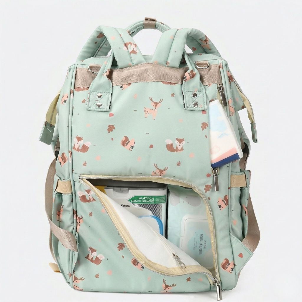 Compartiment principal ouvert du sac à langer vert sauge avec biberons, langes et vêtements bébé rangés