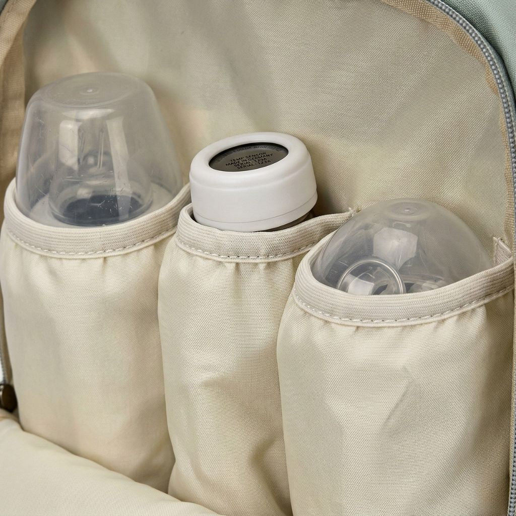 Gros plan sur trois poches isothermes beiges d'un sac à langer accueillant biberons et thermos pour bébé en voyage Image