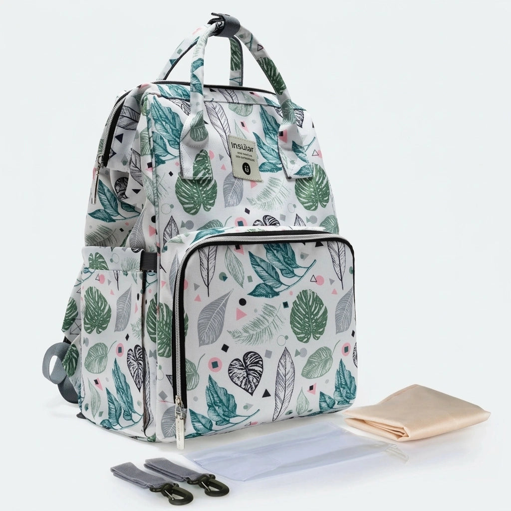 Sac à dos à langer blanc motif feuilles tropicales, vue trois-quarts avec tapis à langer et attaches