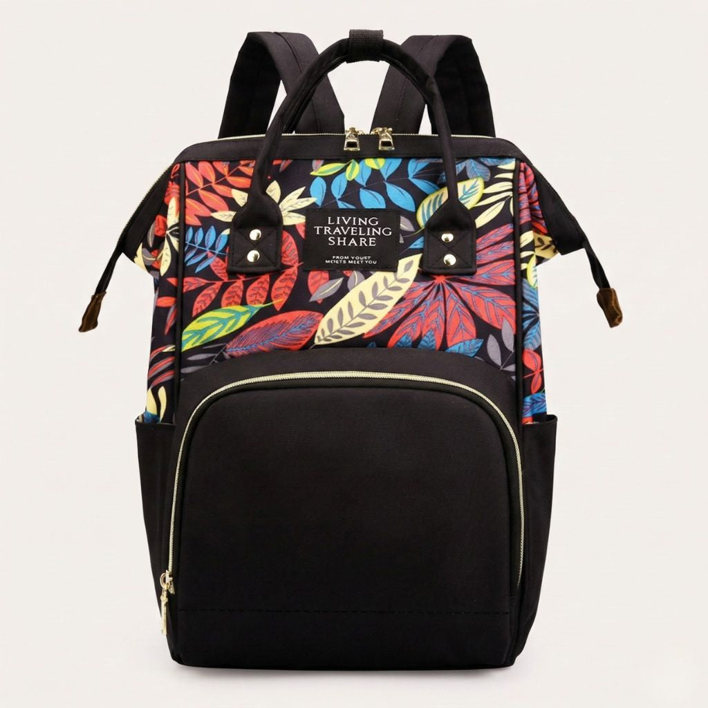 Sac à langer noir à imprimé feuilles tropicales multicolores en haut, vue de face avec poches et fermeture dorée