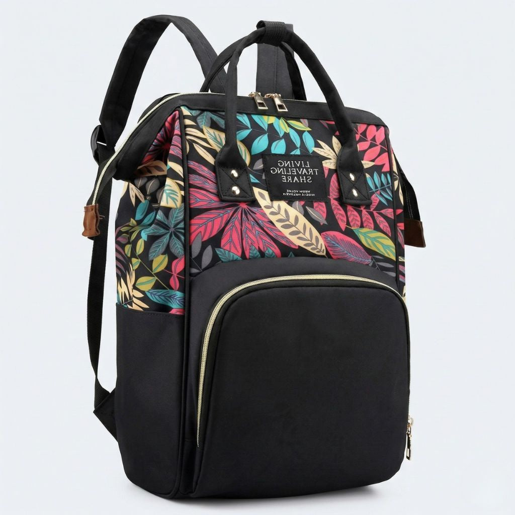 Vue 3/4 du sac à langer noir avec motif feuilles rouges, roses et bleues, doubles poignées et fermeture dorée