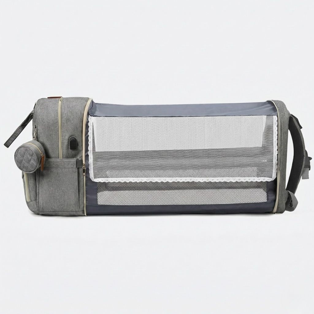 Vue de côté du sac à langer gris chiné avec le lit pliable entièrement déployé et les filets de protection