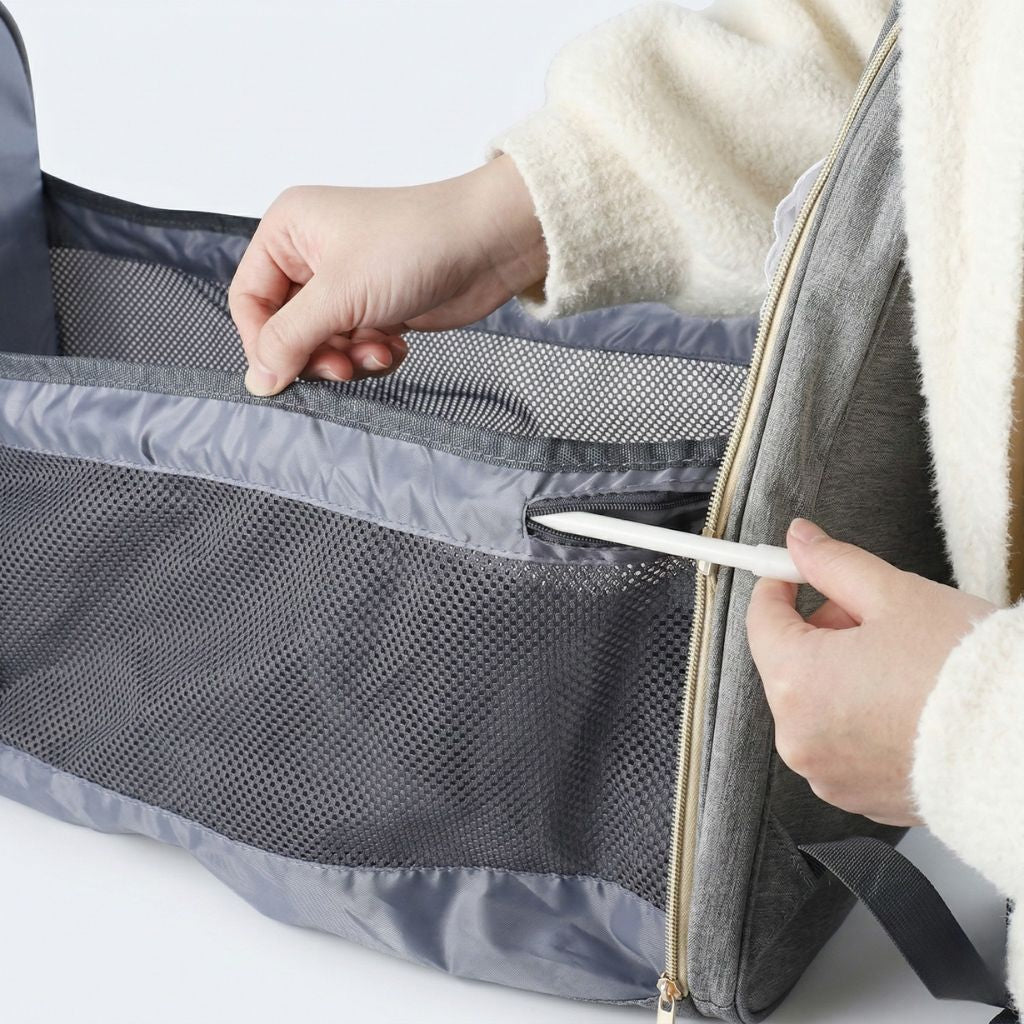 Gros plan de l'intérieur du lit pliable déployé : matelas rembourré, filets latéraux gris et zip doré