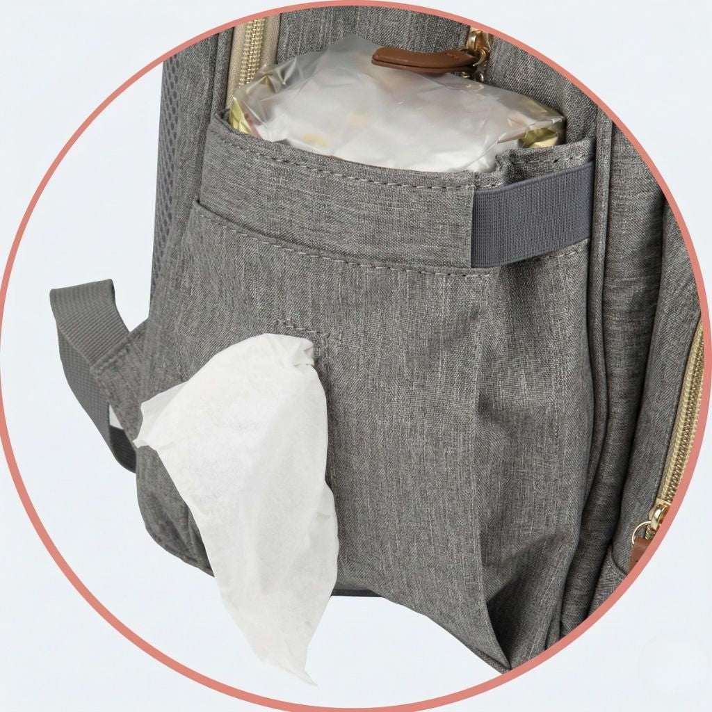 Gros plan poche latérale du sac à langer gris chiné avec distributeur de lingettes et couche roulée rangés