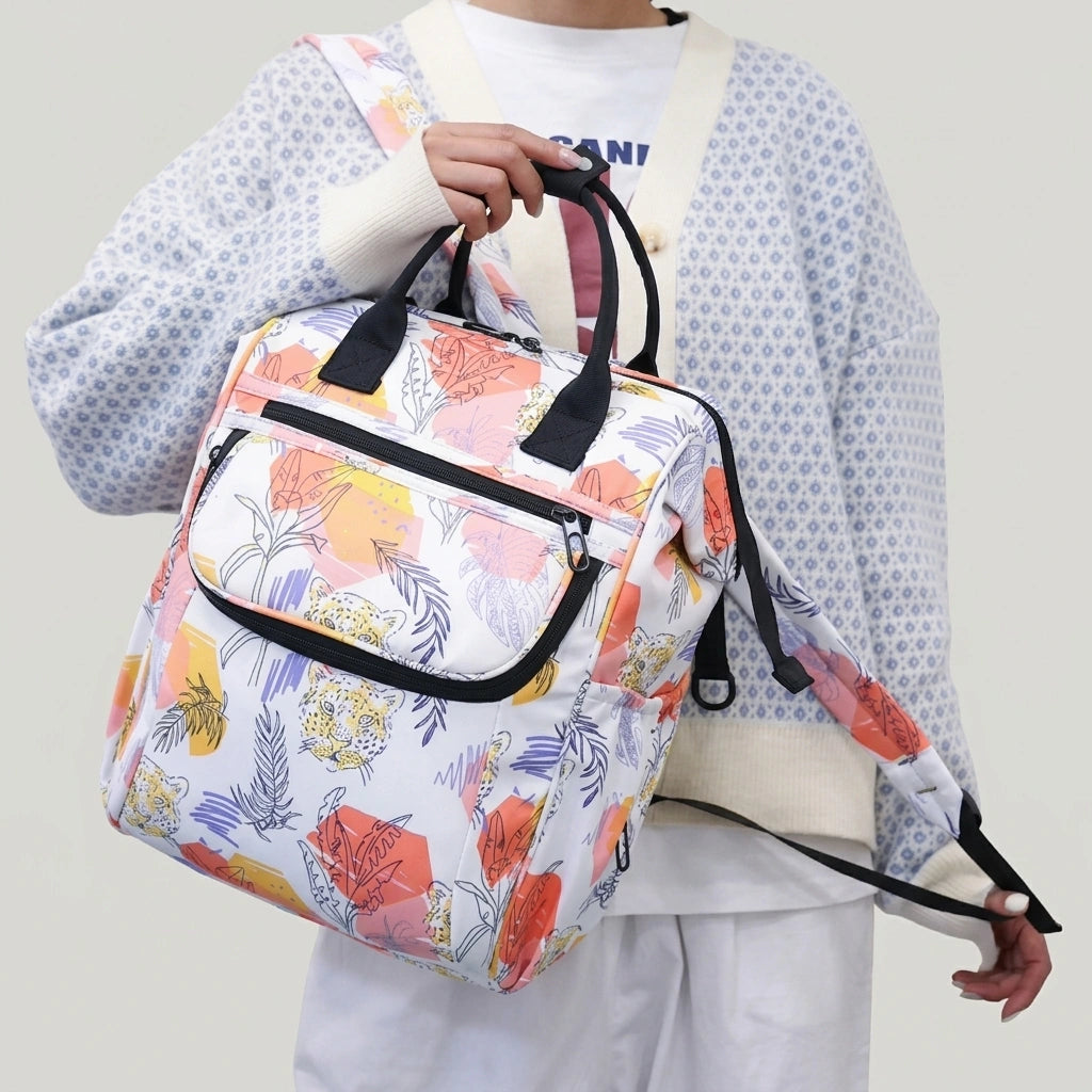 Sac à dos à langer multicolore pastel motif léopards porté à la main, format voyage et balade bébé