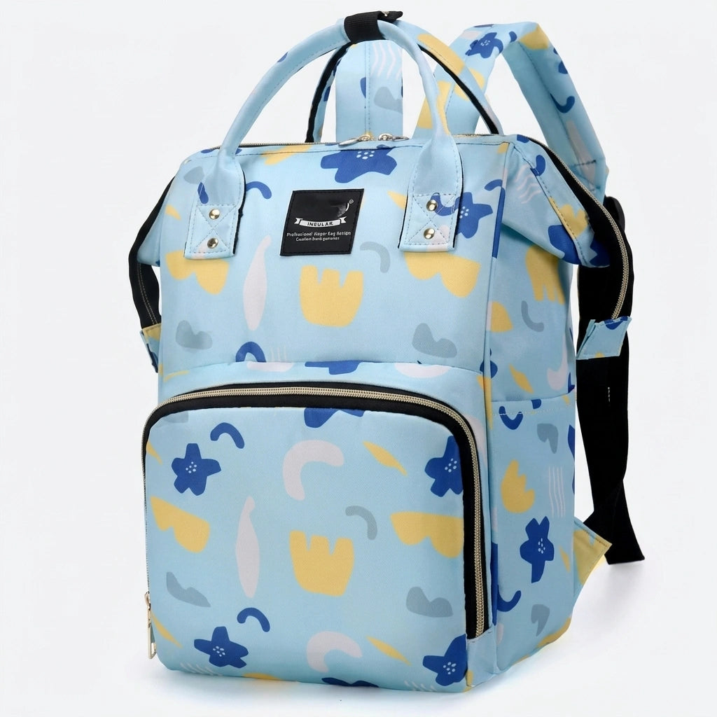 Sac à dos à langer bleu ciel motif fleurs colorées géométriques, vue trois-quarts avec bandoulière