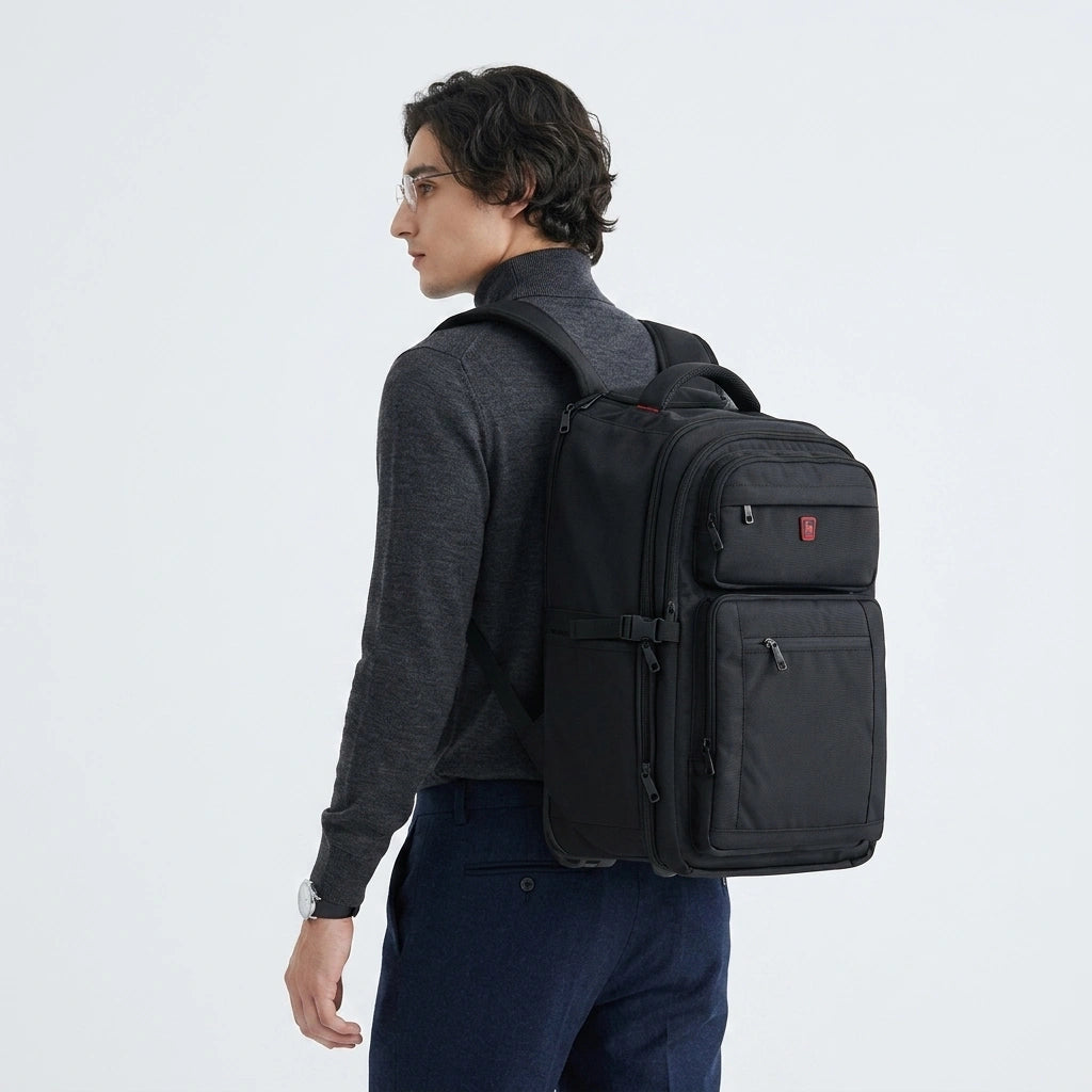Homme en pull gris portant un sac à dos à roulettes noir en mode sac à dos, vue de 3/4 arrière