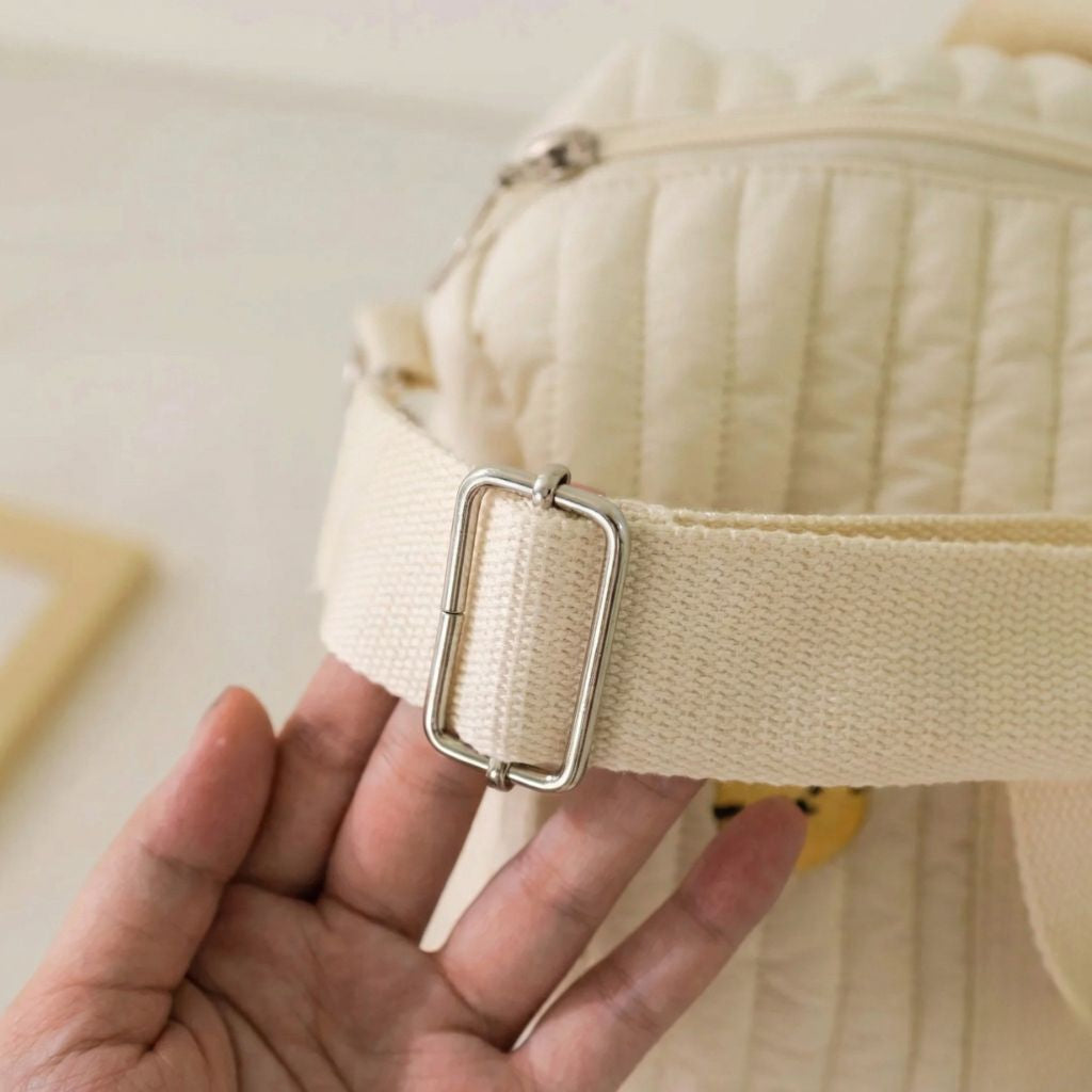 Gros plan sur la bandoulière réglable d'un sac à langer matelassé ourson, boucle métallique argentée