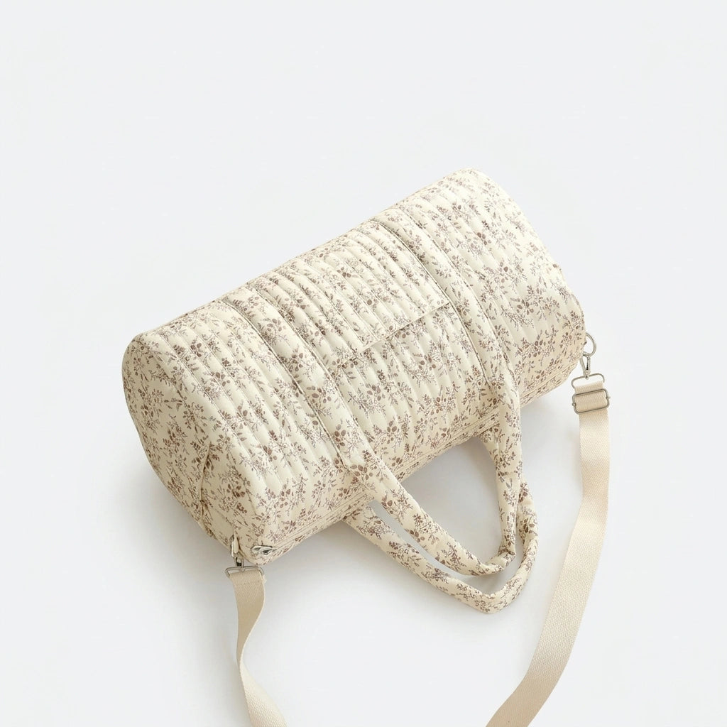 Sac à langer matelassé motif fleurs rose couché au sol, vue du dessus montrant la forme cylindrique