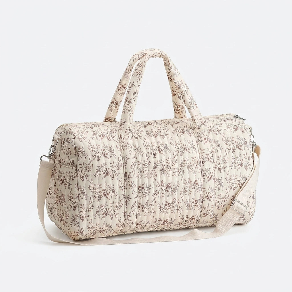 Sac à langer matelassé crème à motif fleuri rose, vue 3/4 avec double poignée et bandoulière réglable