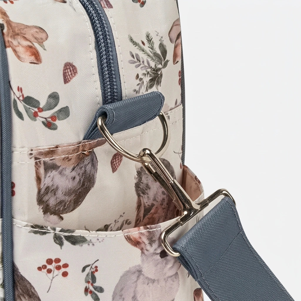Détail des anneaux dorés de fixation de la bandoulière sur le sac à langer imprimé lapins et fruits des bois Image