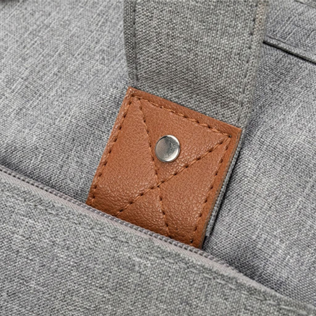 Gros plan du rivet et du bouton cuir fauve ornant la finition du sac gris chiné multifonctions