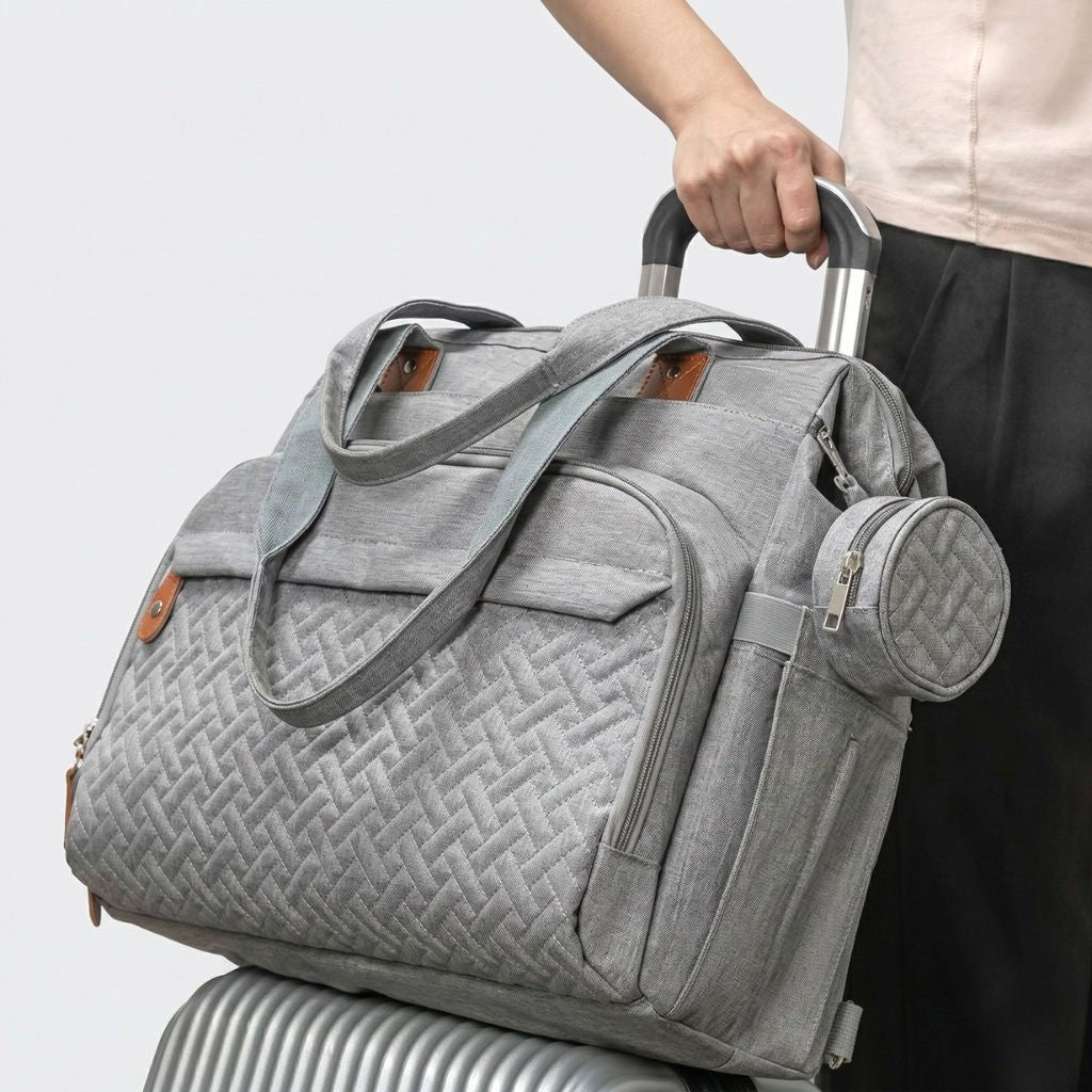 Lifestyle : femme glissant le sac gris chiné sur une valise grâce au passant trolley intégré