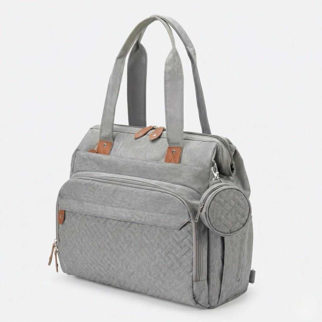 Vue 3/4 du sac multifonctions gris chiné en mode tote bag avec pochette ronde latérale et zips latéraux