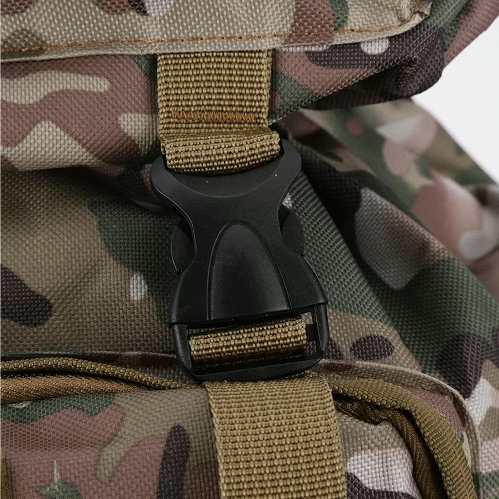 Gros plan sur la boucle de compression noire sur sangle nylon coyote d'un sac à dos tactique camouflage multicam.