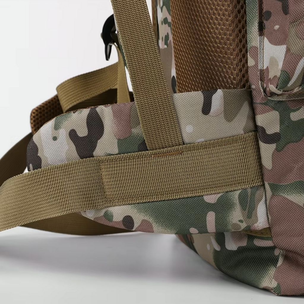 Gros plan sur la poignée de portage en sangle coyote d'un sac à dos tactique en tissu camouflage multicam renforcé.