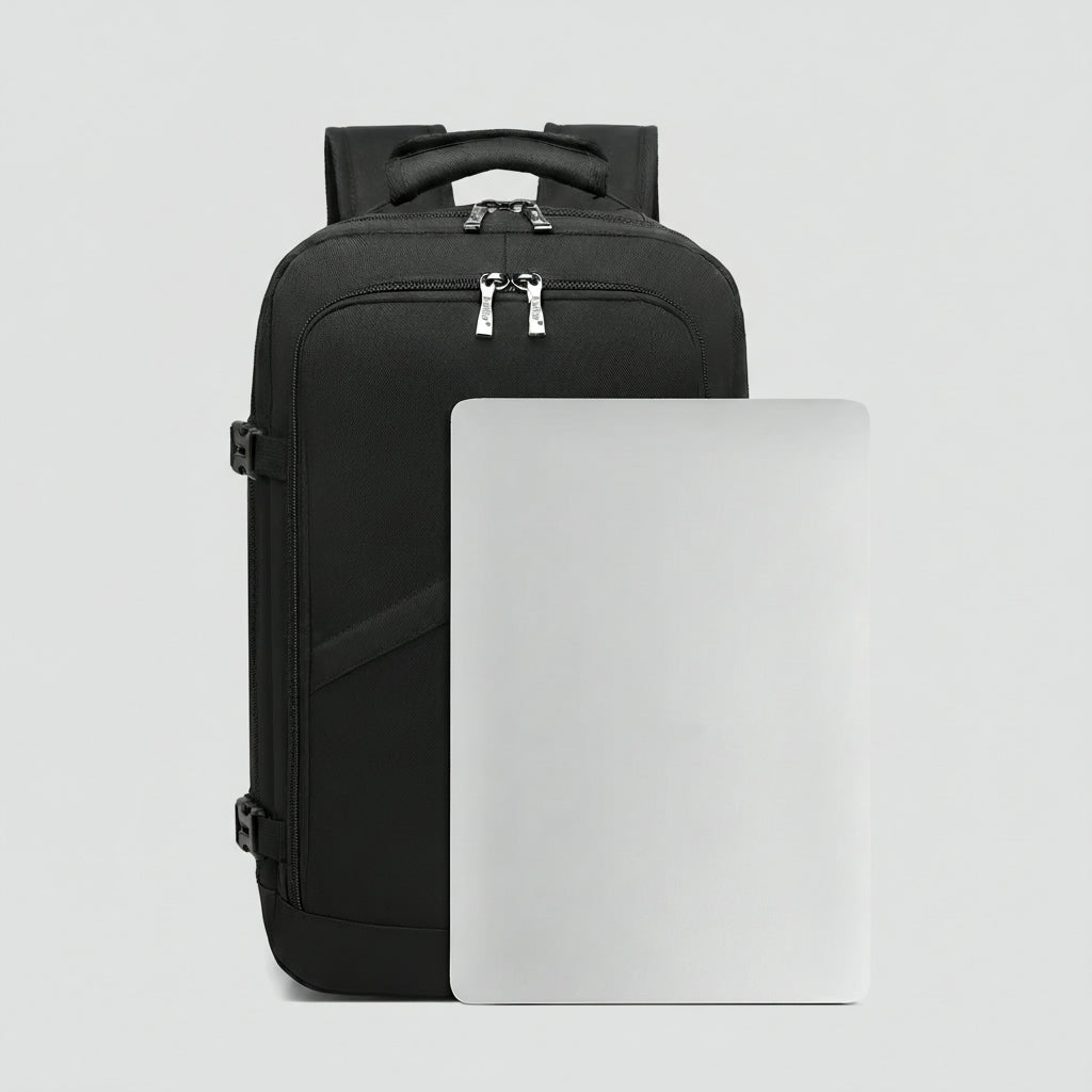 Sac à dos cabine noir de face avec un ordinateur portable posé à côté pour illustrer la contenance