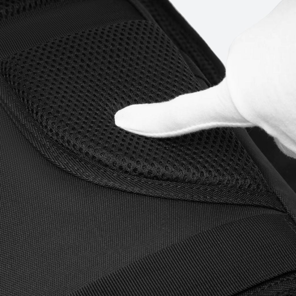 Gros plan de la bretelle rembourrée en mesh du sac à dos, une main gantée appuyant sur le matériau
