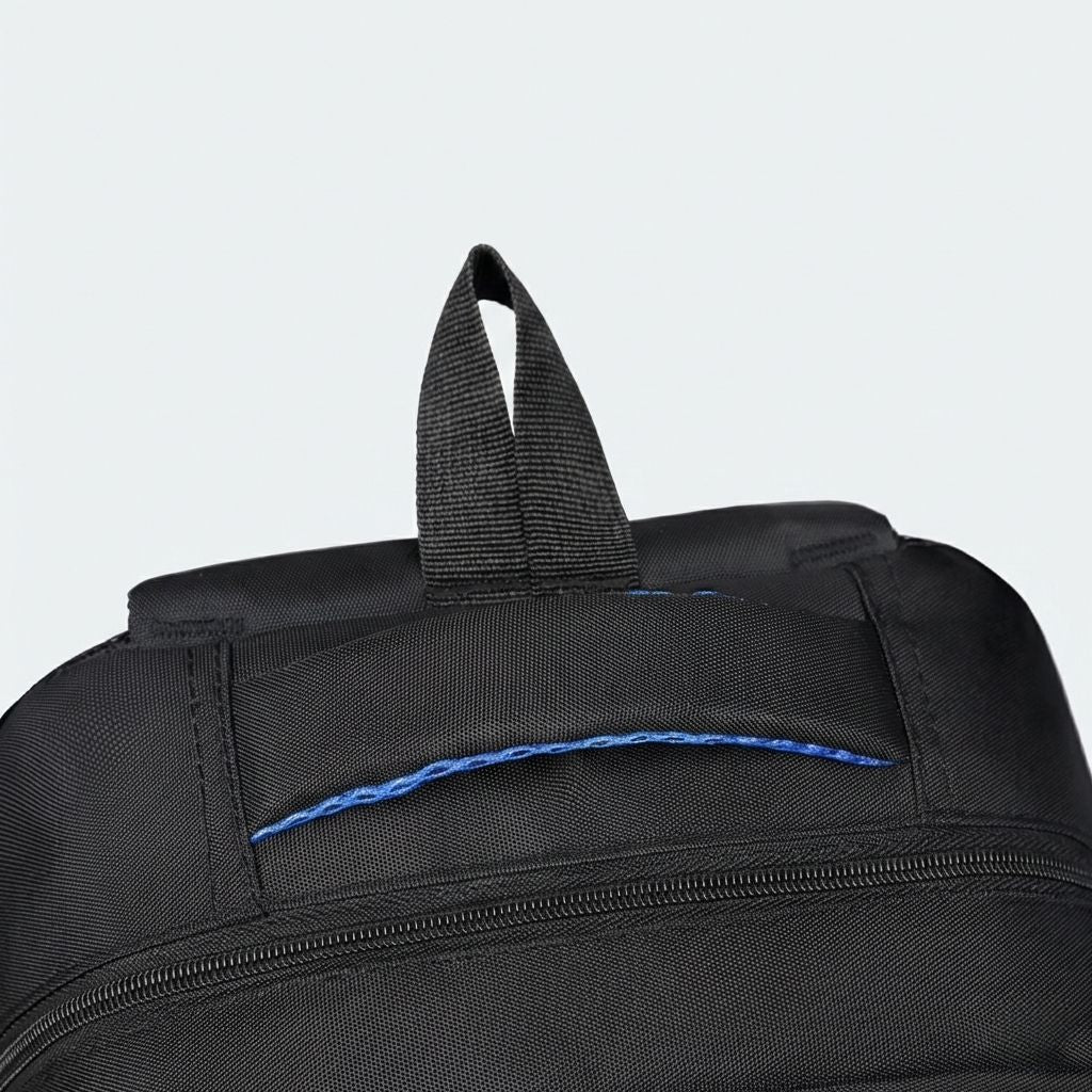 Gros plan du haut du sac à dos noir avec poignée de transport en tissu et doubles tirettes de fermeture bleues