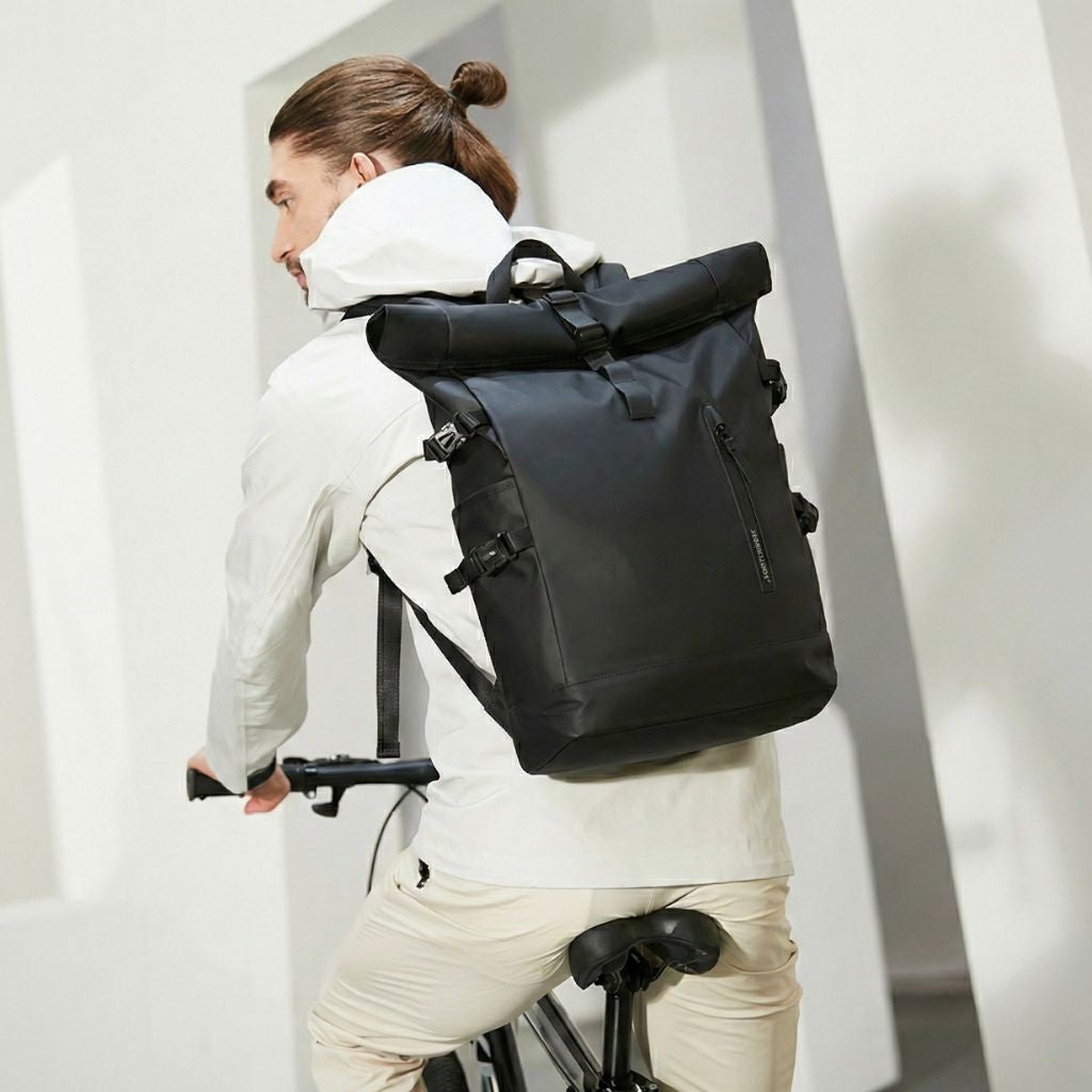 Homme à vélo portant le sac à dos noir roll-top cabine, adapté aux déplacements du quotidien