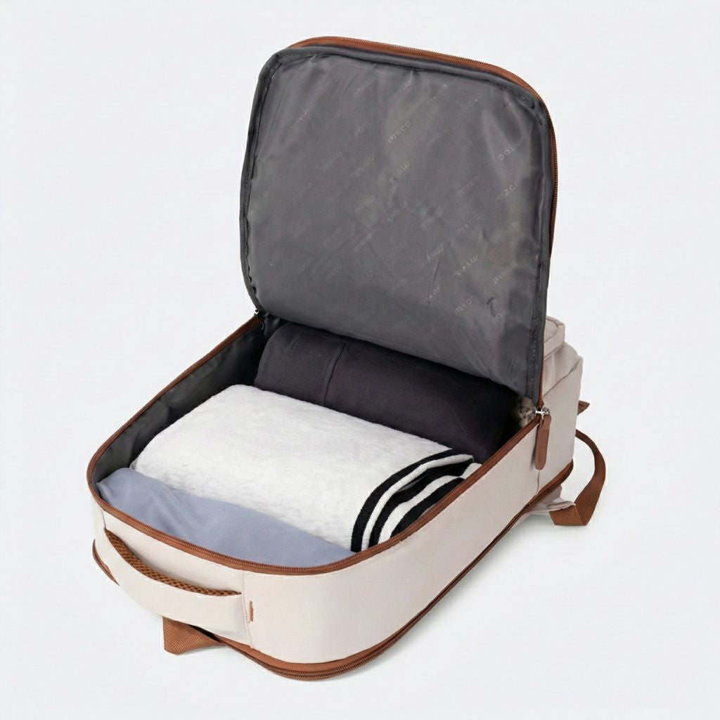 Vue plongeante du compartiment principal d'un sac à dos cabine femme beige ouvert avec vêtements roulés Image