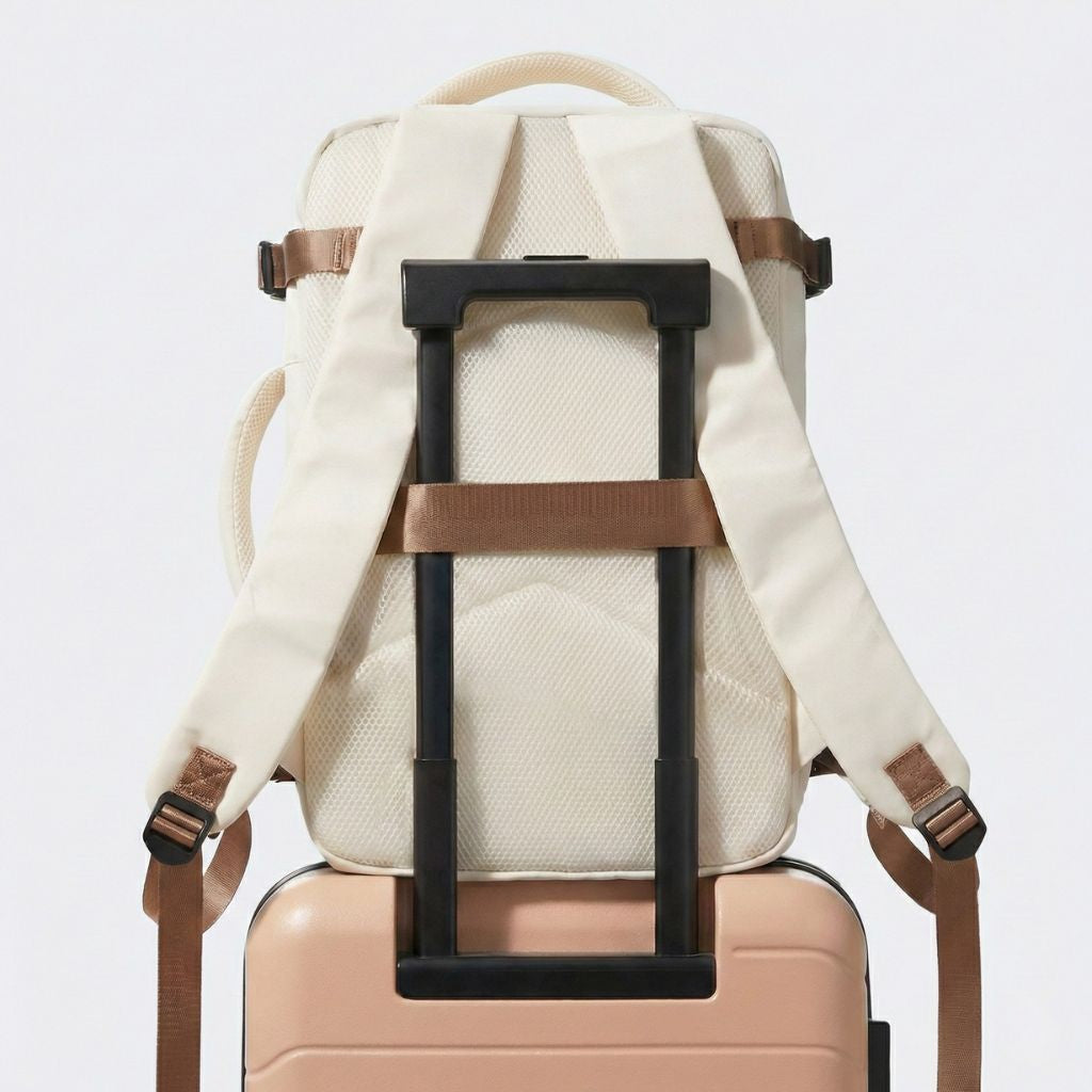 Dos du sac à dos cabine blanc crème posé sur une valise rose, passage trolley et dosseret rembourré