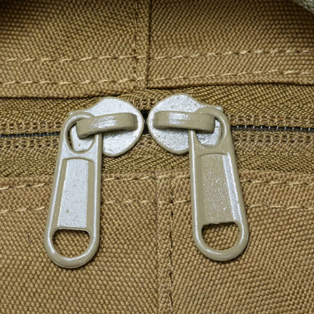 Gros plan des doubles tirettes plastique taupe de la fermeture principale du sac tactique coyote tan