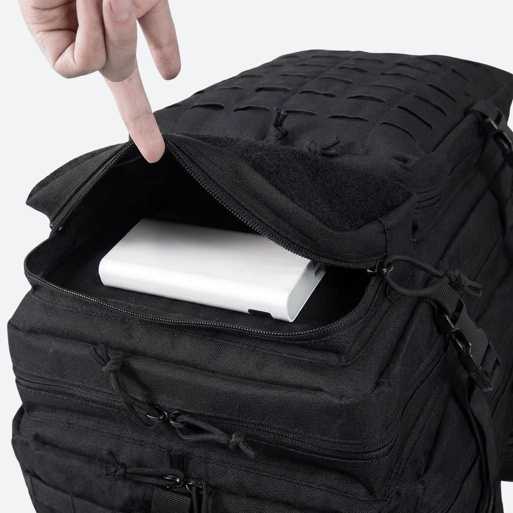 Poche supérieure du sac tactique noir ouverte par une main, banque d'énergie blanche rangée à l'intérieur
